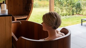 Une baignoire en bois, située dans un cadre de spa, avec vue sur un jardin.