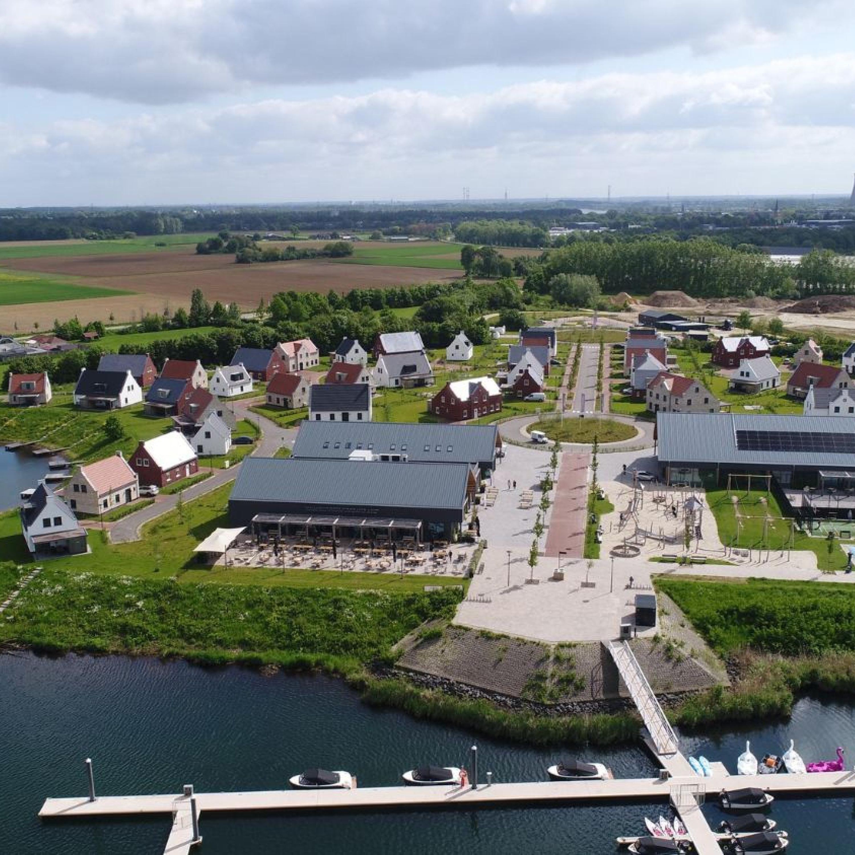 A riverside property with a dock, a large building with a flat roof, and several smaller houses.