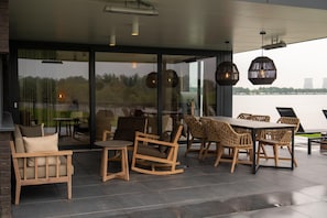 An outdoor patio with wicker furniture, a round table, and hanging lights. - Premium Island 6p in Thorn (Thorn)