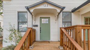 Een houten trap die leidt naar een groene deur, met het cijfer 123 erboven.