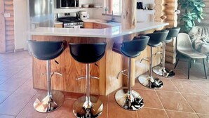 Une cuisine moderne dotée d’un îlot central, de tabourets de bar et d’un coin repas avec une chaise.
