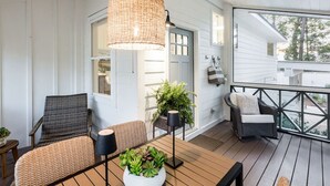 A covered porch with wicker furniture, a hanging light fixture, and potted plants. - Mahi Mahi Cottage in the Woods (Santa Rosa Beach)