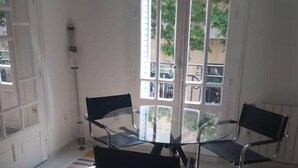 Une pièce avec une table en verre et deux chaises, un sol à motifs et une vue dégagée sur l’extérieur grâce à de grandes fenêtres.