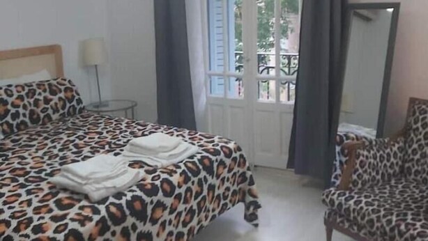 Une chambre à coucher avec un lit, une chaise, une fenêtre et un miroir.