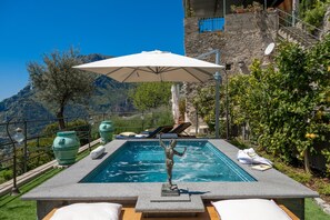 Relax by the serene pool surrounded by lush greenery and a picturesque view.