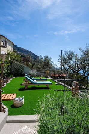 Relax in a serene outdoor space with a lush lawn, lounge chairs, and a small table.
