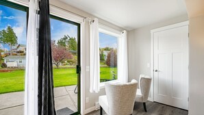 Une pièce dotée d’une porte-fenêtre coulissante donnant sur un patio, de deux fauteuils rembourrés et d’une porte blanche.
