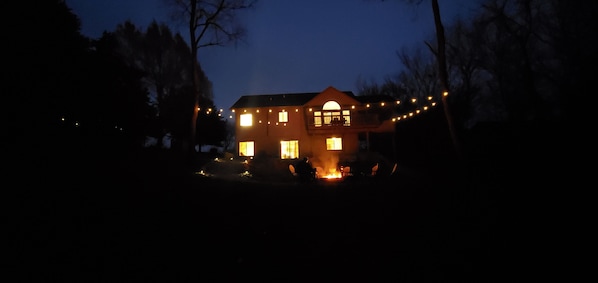 Ein Haus mit einer breiten Veranda und einem Feuer davor.