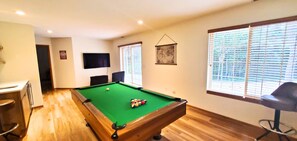 A pool table with balls, a television, and a bar area with stools.
