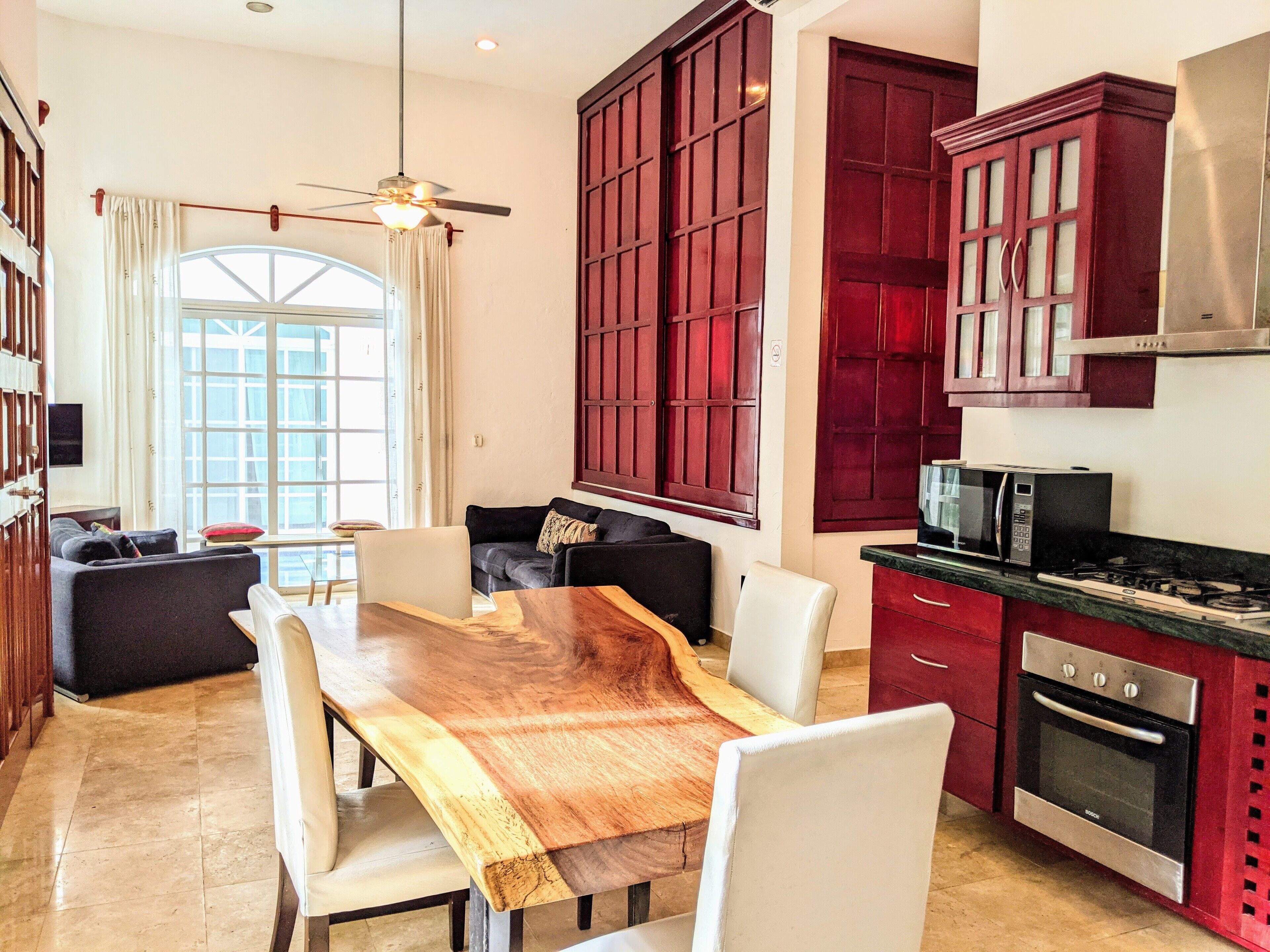 Amplia sala de estar con una mesa de comedor de madera, un sofá y un ventanal grande.