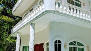 A two-story building with a swimming pool, white exterior, green windows, and a red door. - 9 Bed 6bath  Pool, Roof lounge, Beach Best location in Playa Walk to everything (Playa del Carmen)