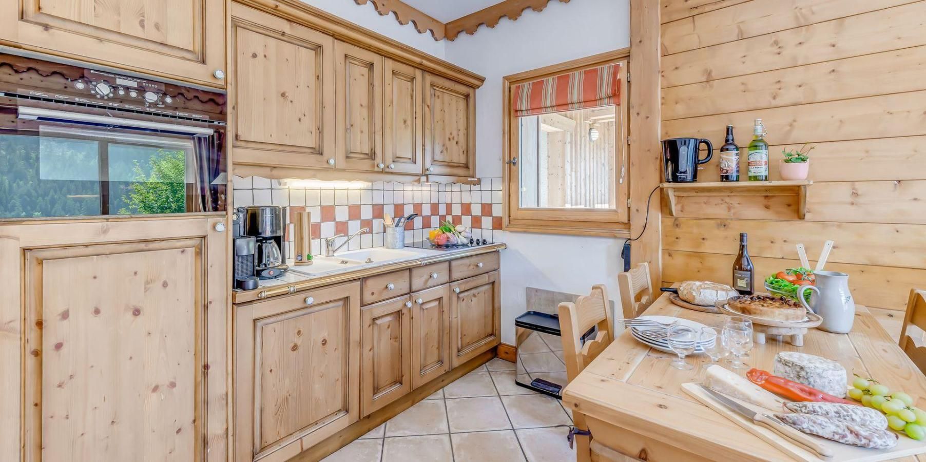 A wooden kitchen with a tiled backsplash, wooden cabinets, a coffee maker, and a dining table set with plates, glasses, and food.