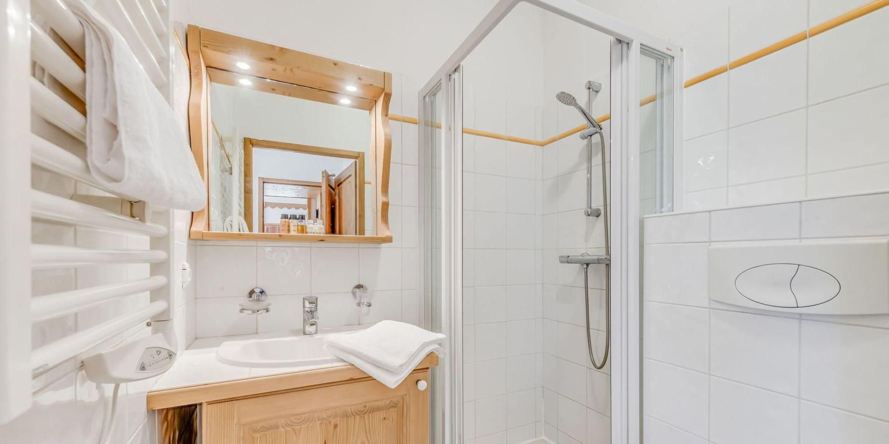 Un baño moderno con cabina de ducha de vidrio, tocador de madera y un espejo grande.