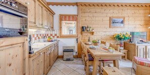 A cozy kitchen with wooden cabinets, a tiled backsplash, and a dining area with a table set for two.