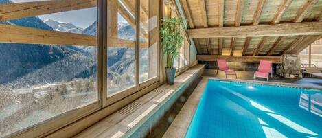 Zona de piscina con vistas a montañas, vigas de madera y una planta en maceta.