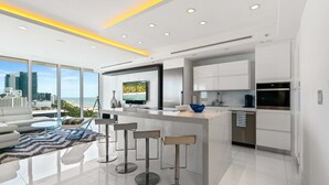 Una cucina moderna con una grande isola, sgabelli da bar e vista sulla città.