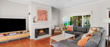 Una sala de estar con televisor de pantalla plana, chimenea, sofá y ventilador de techo.