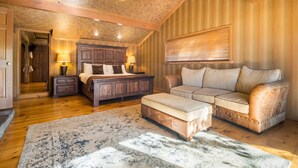 Ein geräumiges Schlafzimmer mit einem großen Bett, einer Couch und einer Holzbalkendecke.