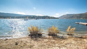 Blick auf einen See mit Booten, einem Steg und einem bewaldeten Hang.