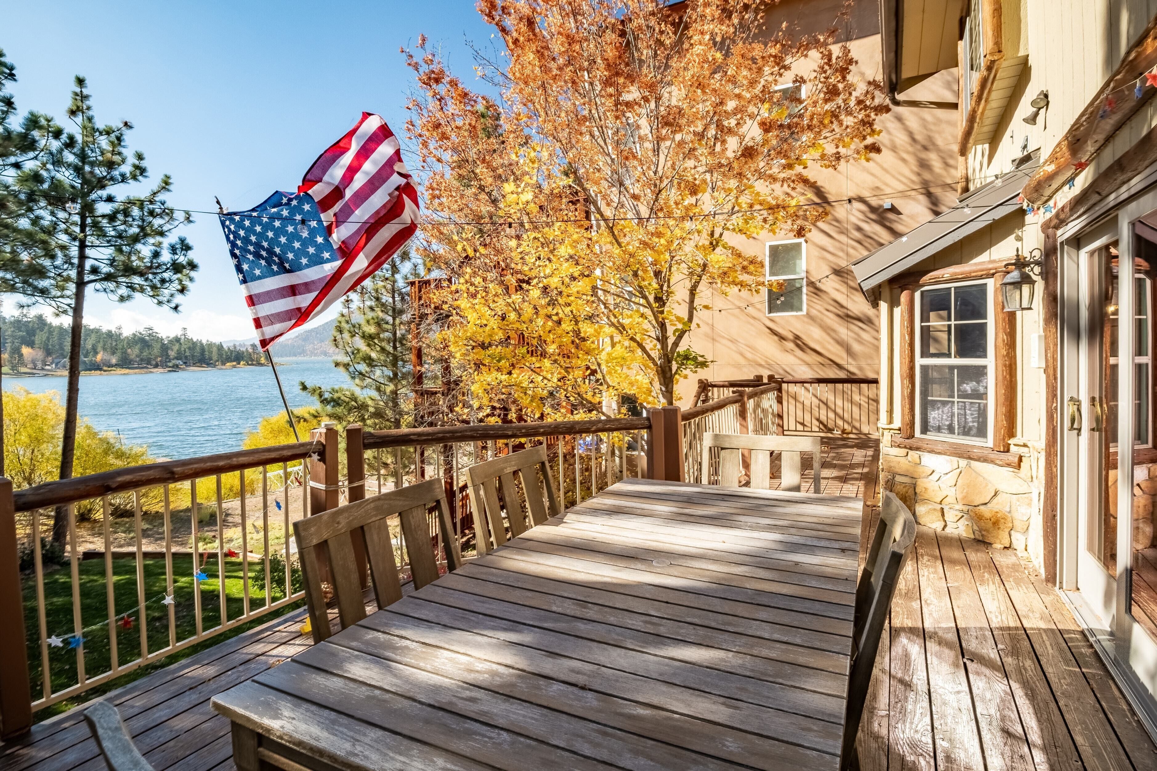 A wooden deck with a view of a lake and autumn foliage.