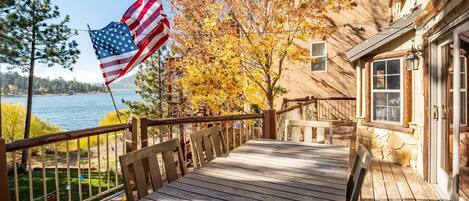 A wooden deck with a view of a lake and autumn foliage.