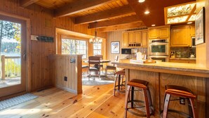 Ein Holzblockhaus-Interieur mit Küche, Essbereich und Bar.