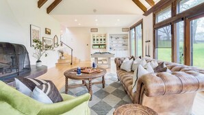 A spacious living room with a fireplace, a leather sofa, a coffee table, and a billiards table. - Malvasia by Avantstay Luxe Wine Country Retreat (Santa Rosa)