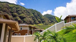 Un quartier résidentiel avec des maisons, une clôture blanche et une montagne en arrière-plan.