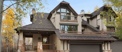 A two-story house with a stone facade, a balcony, and a garage.