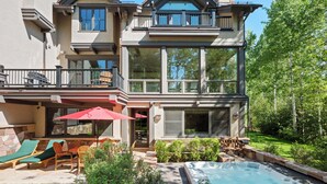A two-story house with a patio area featuring outdoor furniture and a hot tub. - Two Creeks by Snowmass Vacations (Snowmass Village)