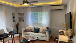 Ein modernes Wohnzimmer mit einer Couch, Sesseln, einem Couchtisch und Dekorationselementen.