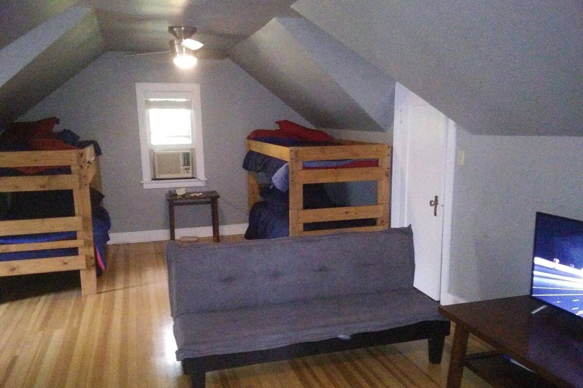 A room with two bunk beds, a sofa, a television, and a small table.