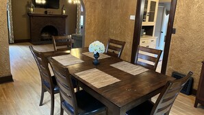 A dining room with a wooden table, six chairs, and a chandelier.