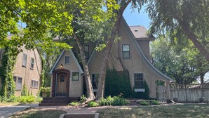 A two-story house with a steeply pitched roof, a front porch, and a brick entrance.