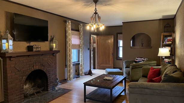 A living room with a fireplace, a television, a chandelier, a sofa, and a coffee table.