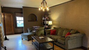 A cozy living room with a sectional sofa, a wooden coffee table, and a chandelier.