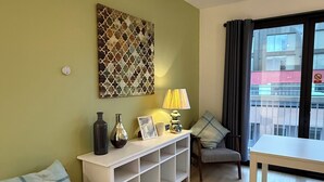 A living room with a sofa, a white console table, a lamp, and a painting on the wall. - Two Bedroom Balcony Apartment Liverpool  (Liverpool)