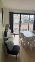 Un área de comedor con una mesa, sillas, una lámpara, una botella y una silla con cojín.