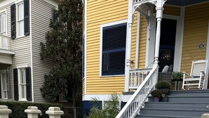 A residential house with a white picket fence, a front porch with a staircase, and a yellow exterior. - Perfect historic location between beach and strand  (Galveston)