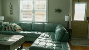 Un divano in pelle verde con un tavolino in legno, una lampada e una decorazione a forma di pesce sul muro.