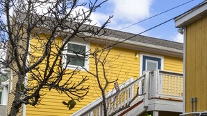 A yellow building with a staircase leading to a balcony. There is a bench and a grill outside. - Perfect historic location between beach and strand  (Galveston)