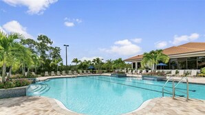 A swimming pool with lounge chairs and palm trees. - Bright corner unit with Pond View Overlooking Hole 8 at Naples Heritage (Naples)