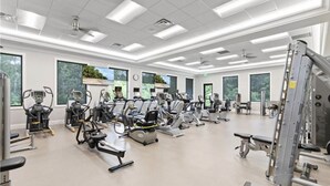 A gym with various exercise machines, large windows, and a clean, modern design. - Bright corner unit with Pond View Overlooking Hole 8 at Naples Heritage (Naples)
