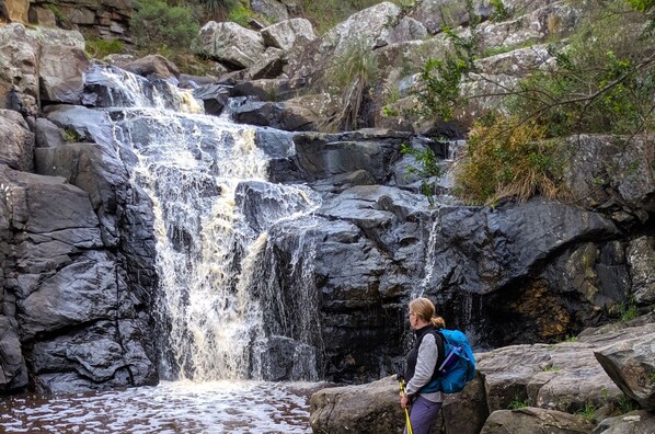 A waterfall in a rocky area with a person standing nearby. - Nature stay Ridgetop Retreat (Deep Creek National Park)