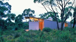 A modern, single-story house with a large glass door and a small attached structure.