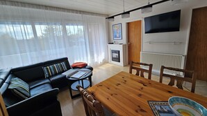 Ein modernes Wohnzimmer mit einem Holzesstisch, einer schwarzen Ledersofa und einem Kamin.