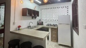 A compact kitchen with a central island, bar stools, a refrigerator, and pendant lighting. - El Caracol Azul #2, Punta Uva Beach (Punta Uva)