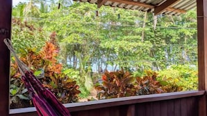 A hammock under a wooden pergola with a view of lush greenery and a metal fence. - El Caracol Azul #2, Punta Uva Beach (Punta Uva)