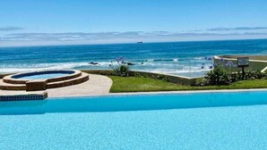 Una piscina con vistas al océano, un jacuzzi circular y un cartel.