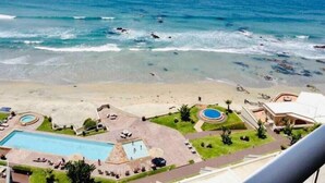Un resort con piscina, cancha de tenis y vista al océano.